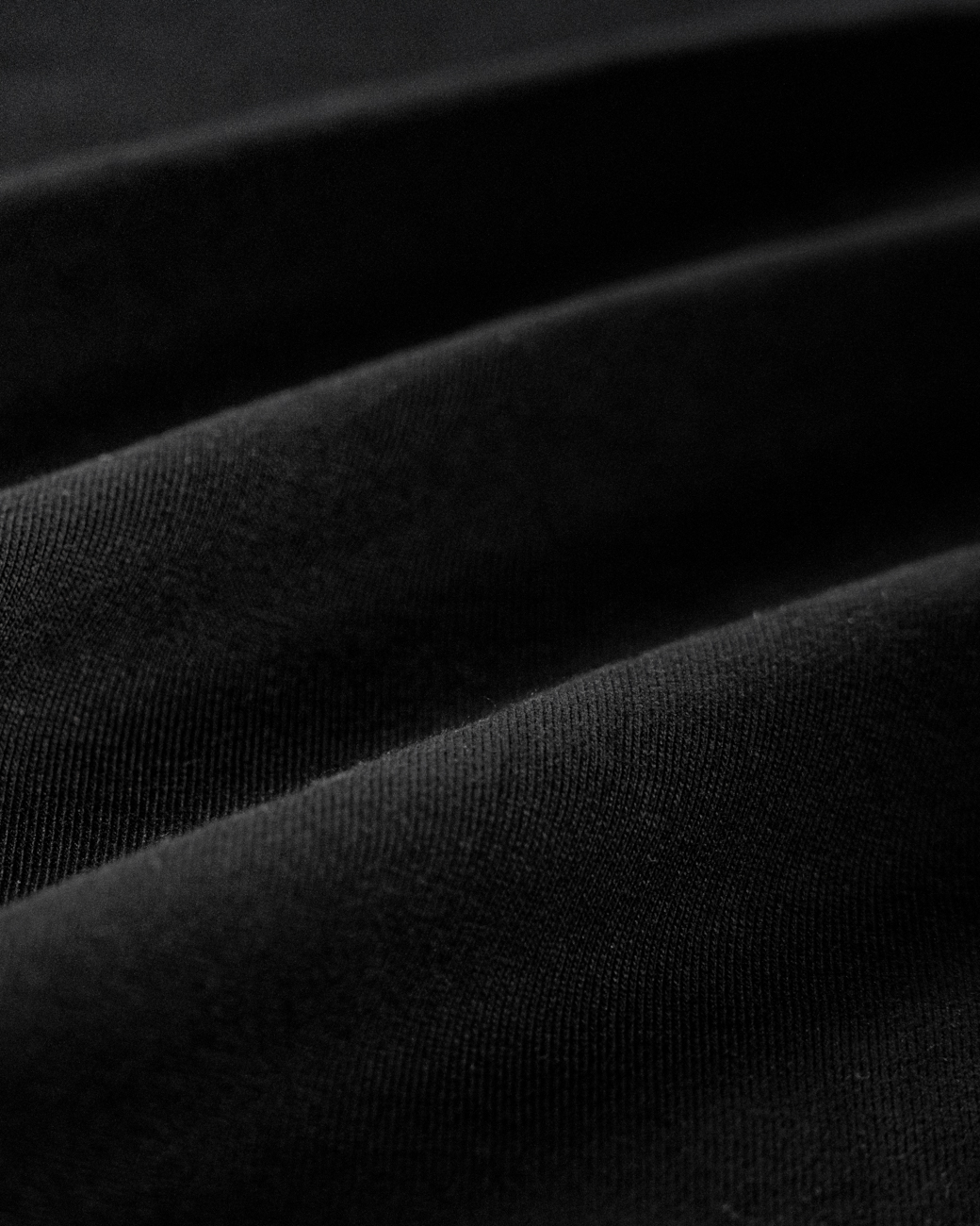 Premium Baumwoll-Stoff – Stancers Material-Detail Nahaufnahme der hochwertigen, fein gewebten Baumwollstruktur eines schwarzen Stancers T-Shirts.